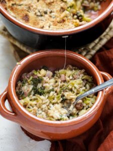 small terracotta dish with rice, cabbage and bacon with a spoon