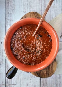 terracotta pot with ragu sauce and a ladle inside