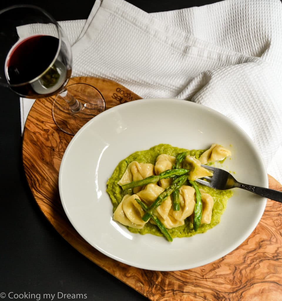 overhead dish with tortelli and asparagus with a glass of red wine
