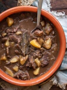 spoon in a terracotta pot with venison and potatoes stew