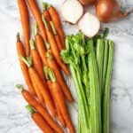 carrots, celery and onions on a board