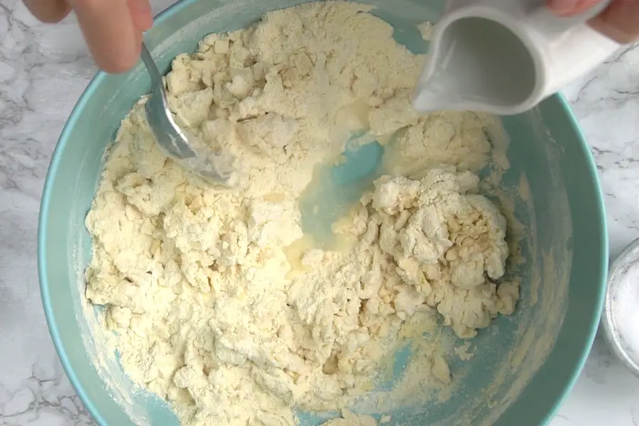 fork mixing the flour while water is added to the bowl