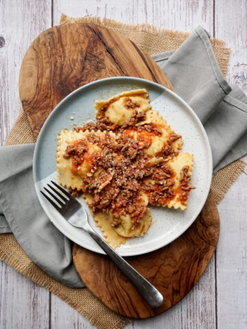 overhead shot of a plate with ravioli and ragù sauce