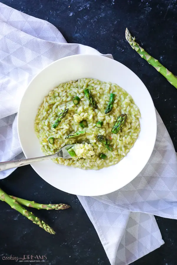 overhead photo of asparagus risotto in white dish