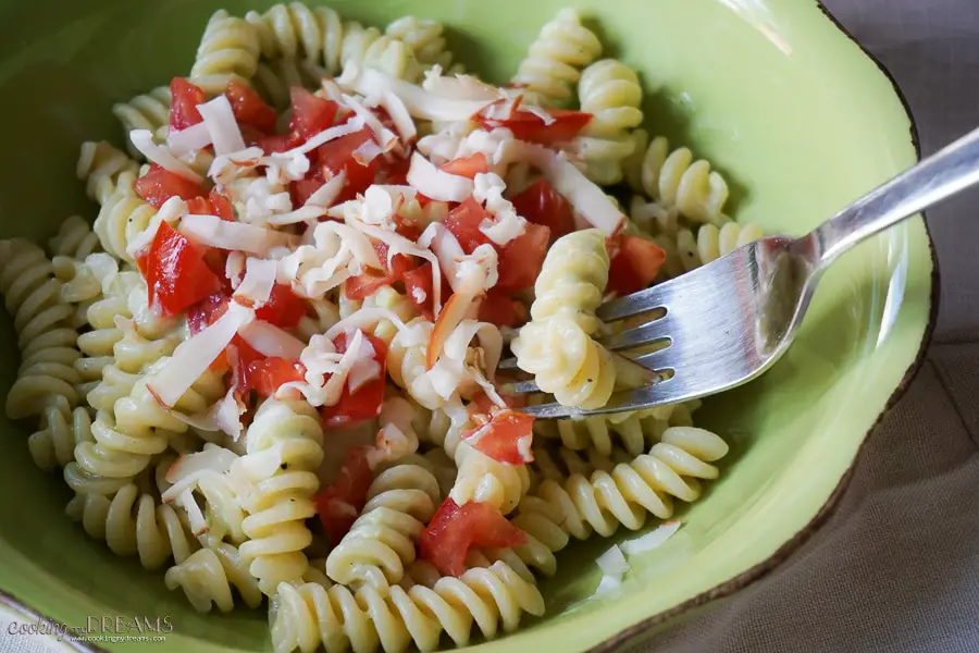 green plate with fusilli pasta, avocado sauce and cherry tomatoes