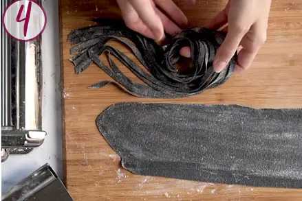 cutting squid ink tagliatelle through a pasta machine.