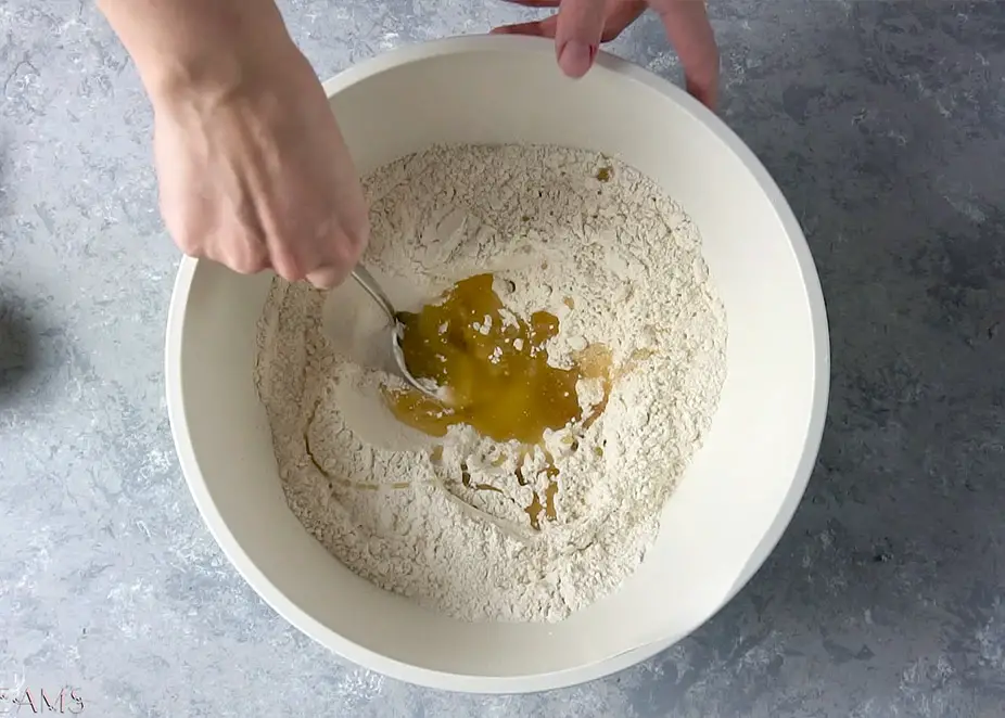hand mixing focaccia ingredients in a bowl with a fork