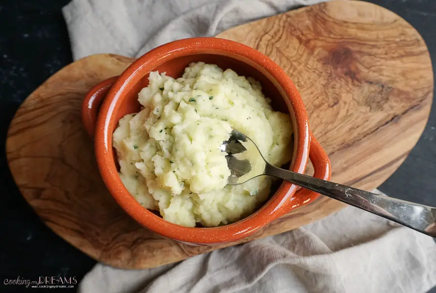 garlic mashed potatoes in terracotta bowl with a spoon