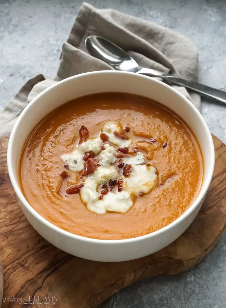 bowl of sweet potato soup with melted cheese and bacon