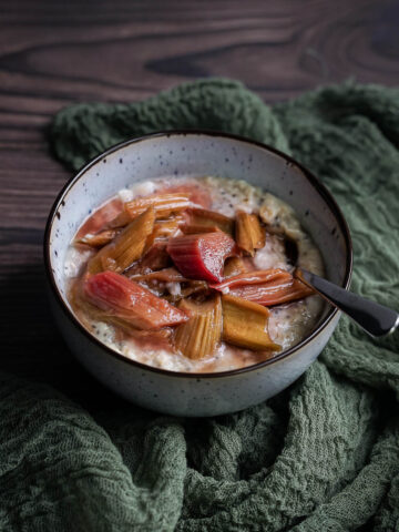 vanilla oatmeal in a bowl topped with roasted rhubarb and a spoon