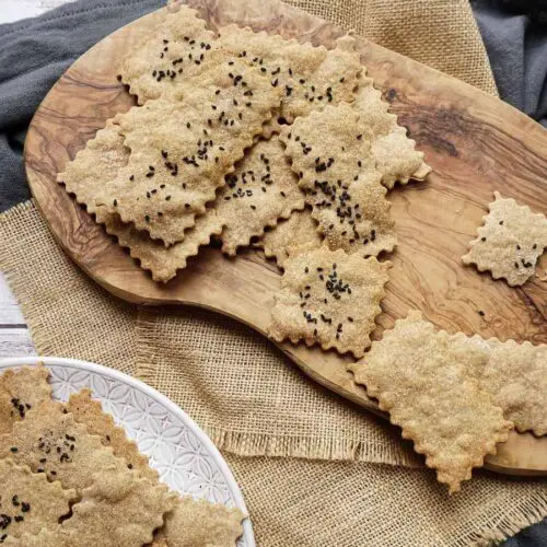 cumin spelt crackers on a plate and on a wooden board