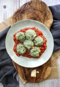 plate on a wooden board with tomato sauce and spinach and ricotta gnocchi