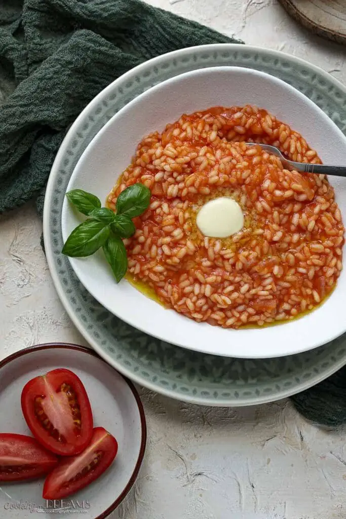 tomato risotto with basil, a slice of butter and a fork