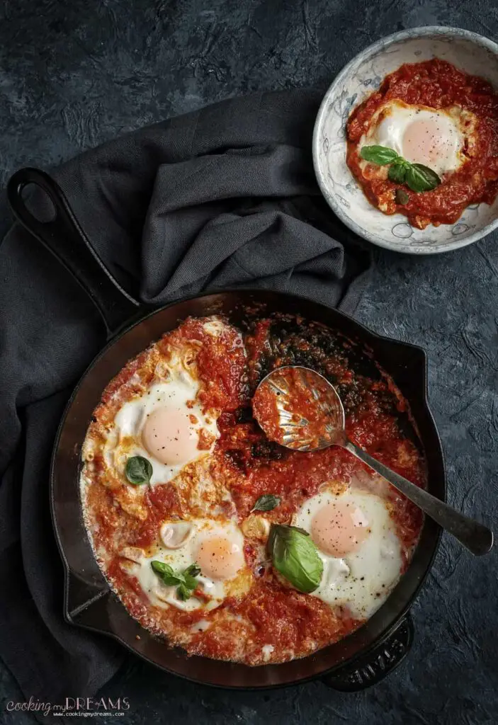 eggs in purgatory in skillet with a spoon and a portion in a bowl
