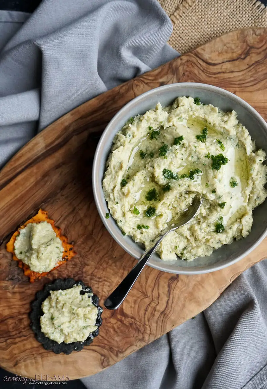 Bowl of artichoke dip with crackers on a side