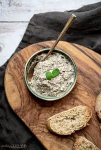 bowl of mushroom pate with spoon next to slices of bread