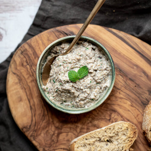 bowl of mushroom pate with spoon next to slices of bread