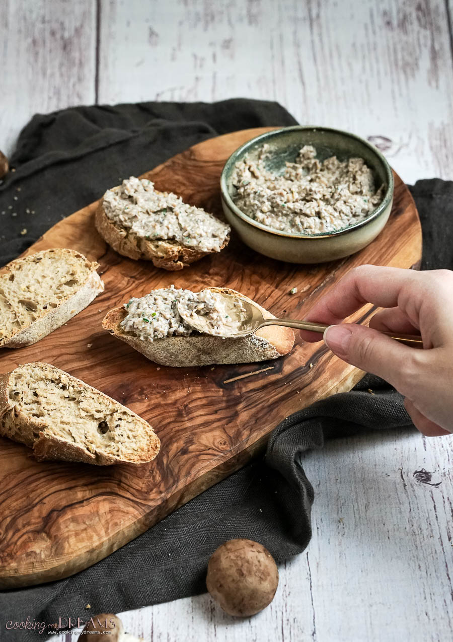 hand with a spoon spreading the patè on a slice of bread