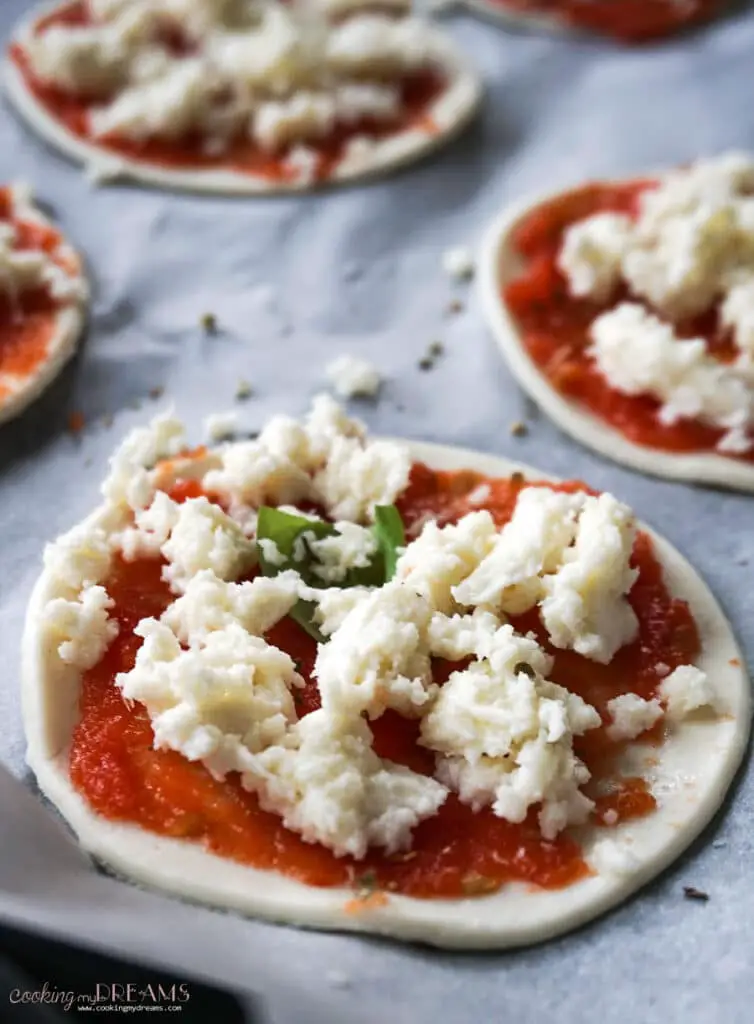 close up of raw mini pizza with tomato and mozzarella
