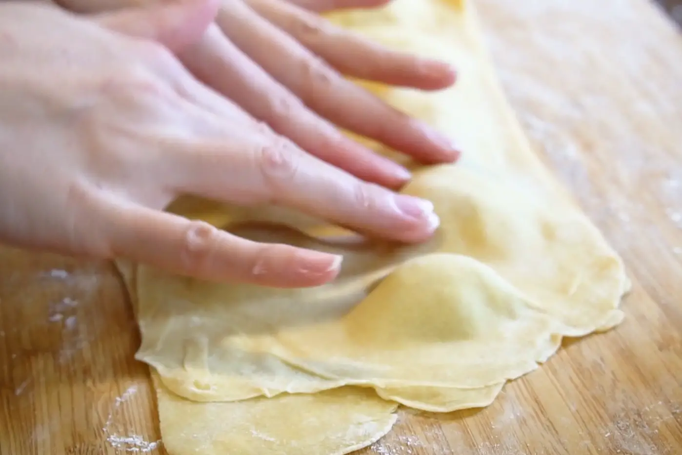 hands pressing the pasta around the ravioli filling