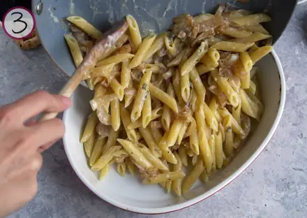 hand pouring pasta into a casserole dish with a spoon