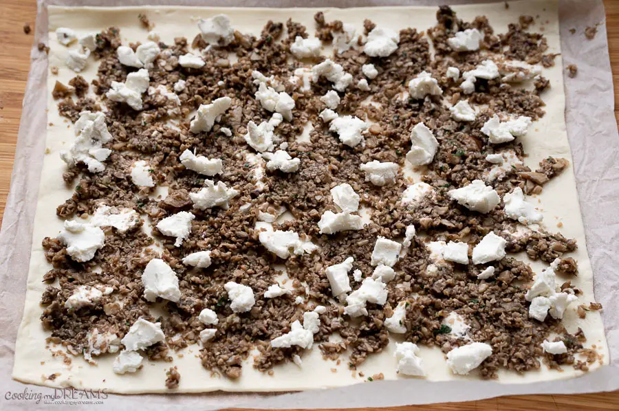 raw dough sheet topped with mushrooms and goat cheese