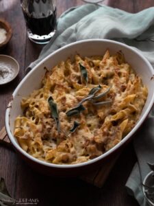 baked french onion pasta bake on a table with sage leaves on top