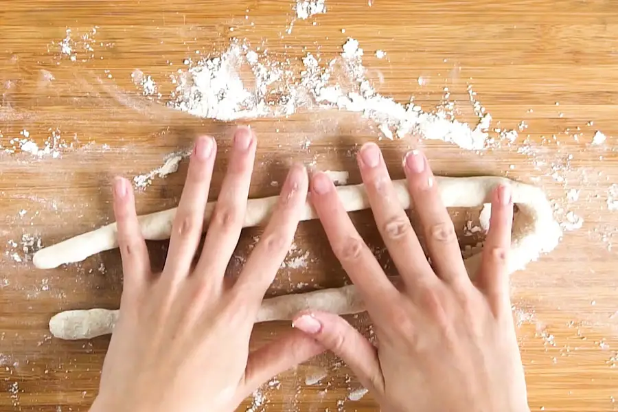hands rolling the gnocchi dough on a wooden board