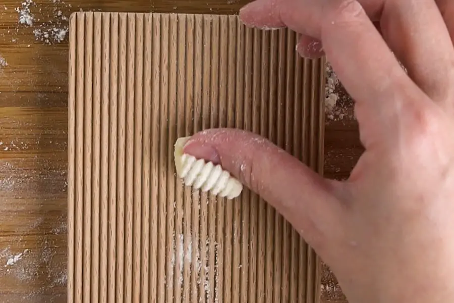 fingers rolling gnocchi on a gnocchi board