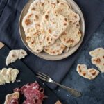 plate full of mini flatbreads next to a charcuterie board