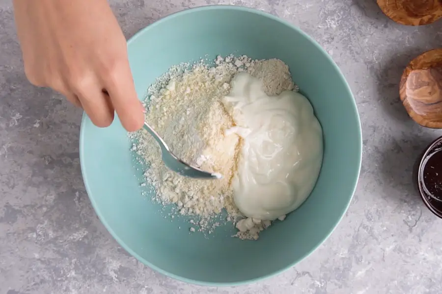 spoon mixing the ingredients for flatbread in a bowl