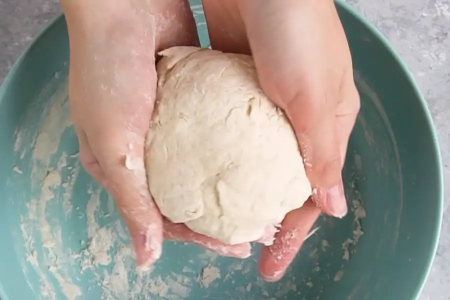 hands kneading a ball of flatbread dough