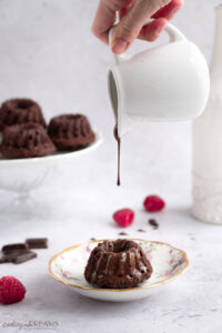 hand holding jug pouring chocolate glaze over mini bundt cakes