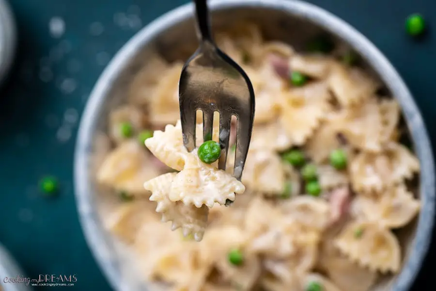 fork holding a bowtie pasta with peas
