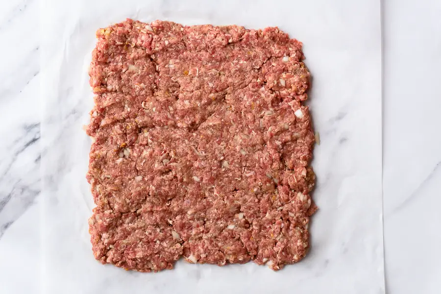 ground beef spreaded on parchment paper into a square