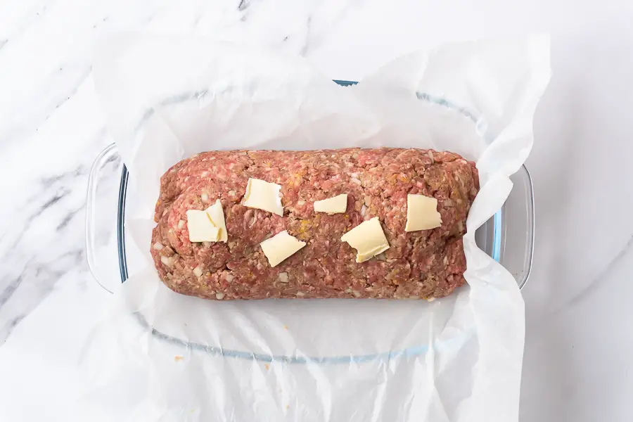 slices of butter added on top of the raw meatloaf