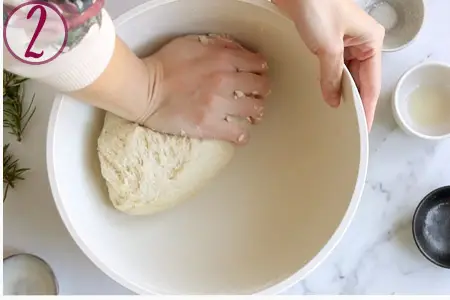 hand kneading the bread dough in a bowl
