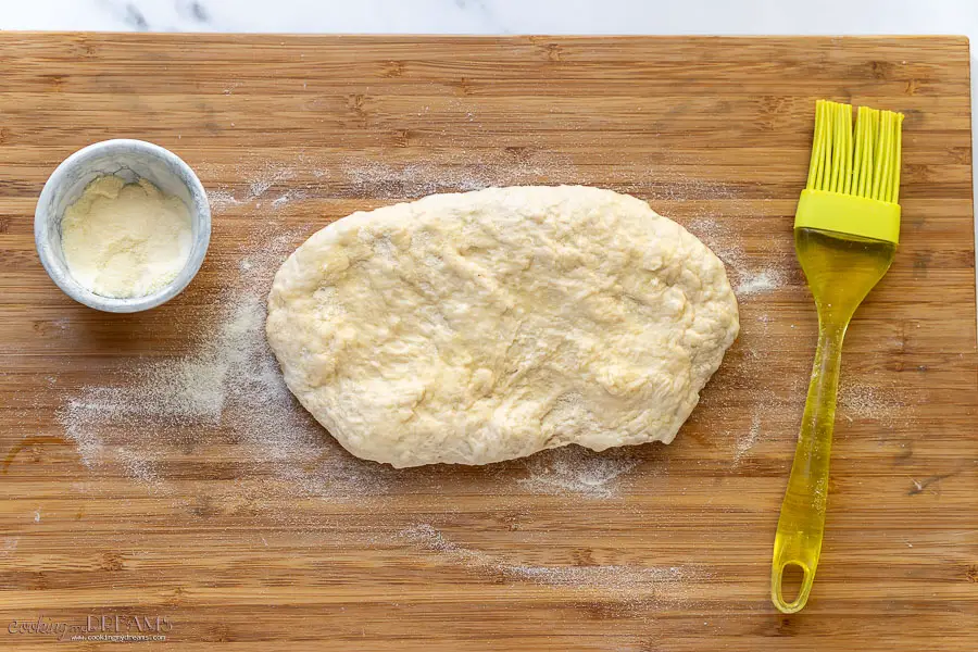 dough stretched on a wooden board dusted with semolina