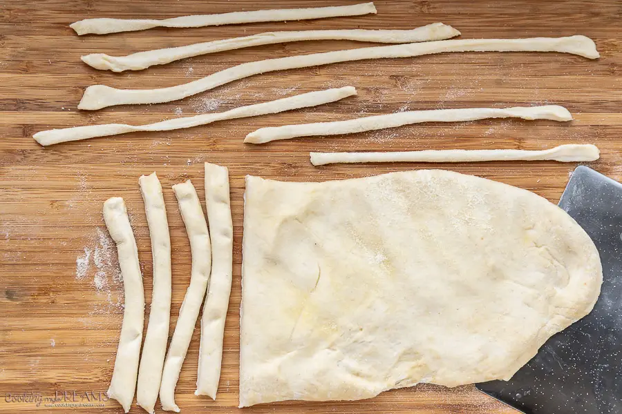 the dough is cut into strips on a wooden board
