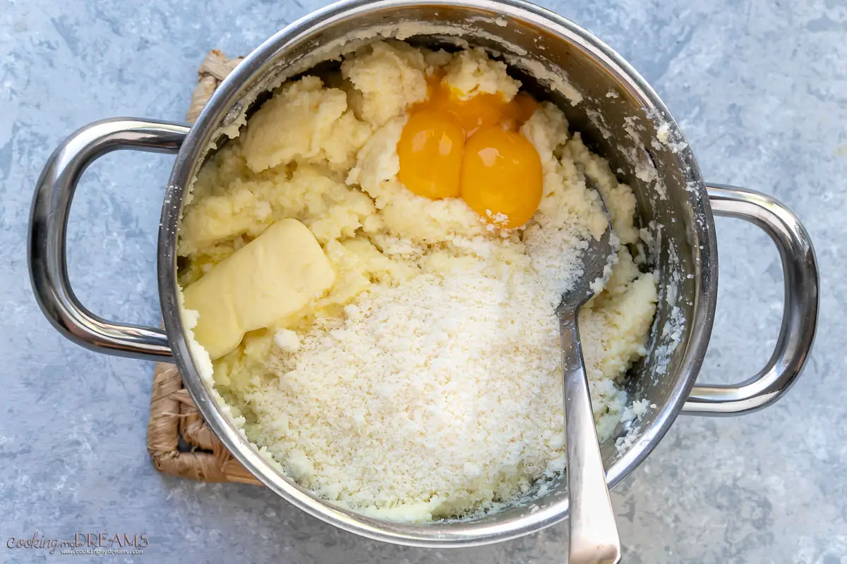 spoon mixing semolina with cheese and eggs in a pot