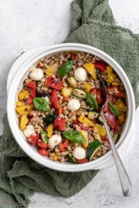 overhead of bowl full of grilled vegetables farro salad with a spoon