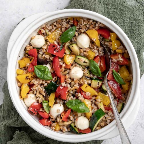 overhead of bowl full of grilled vegetables farro salad with a spoon
