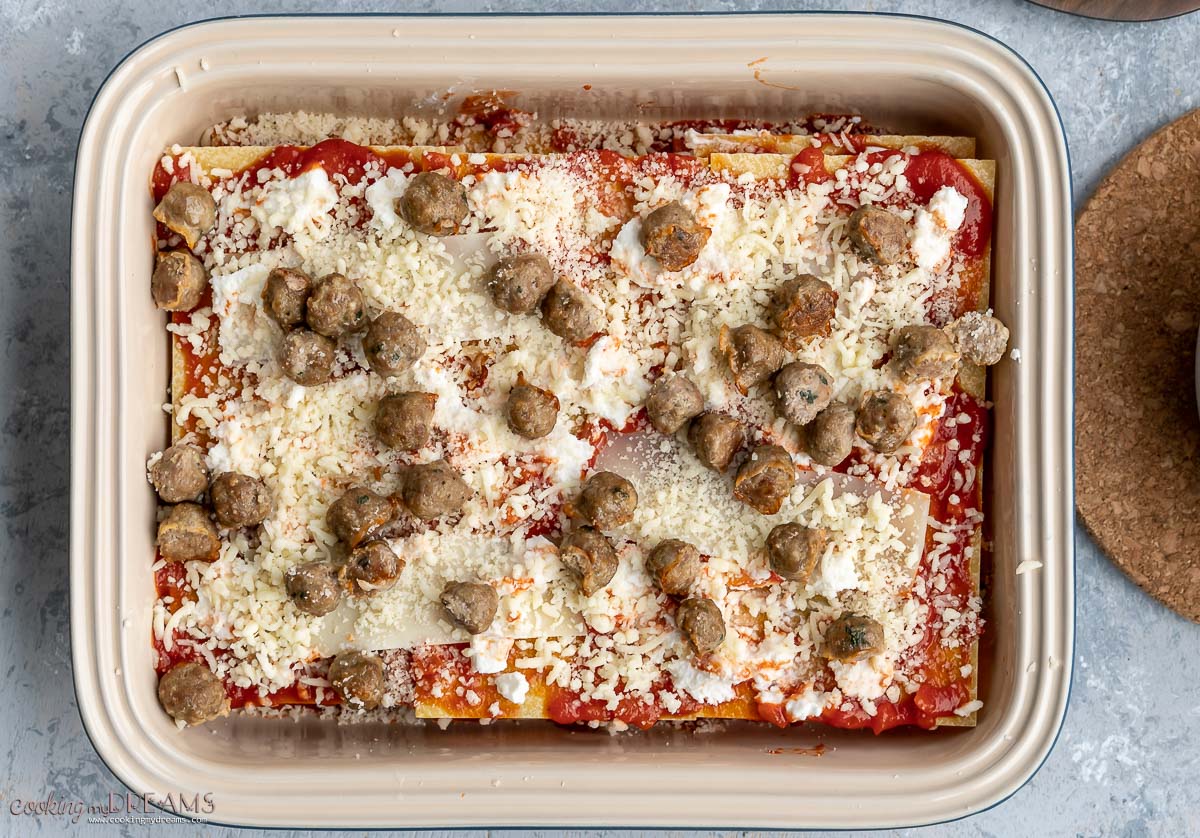 meatballs and more cheese are added as a layer in the lasagna