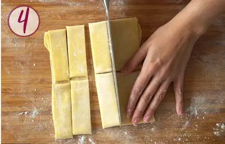 hands cutting with a knife a pasta sheet into strips