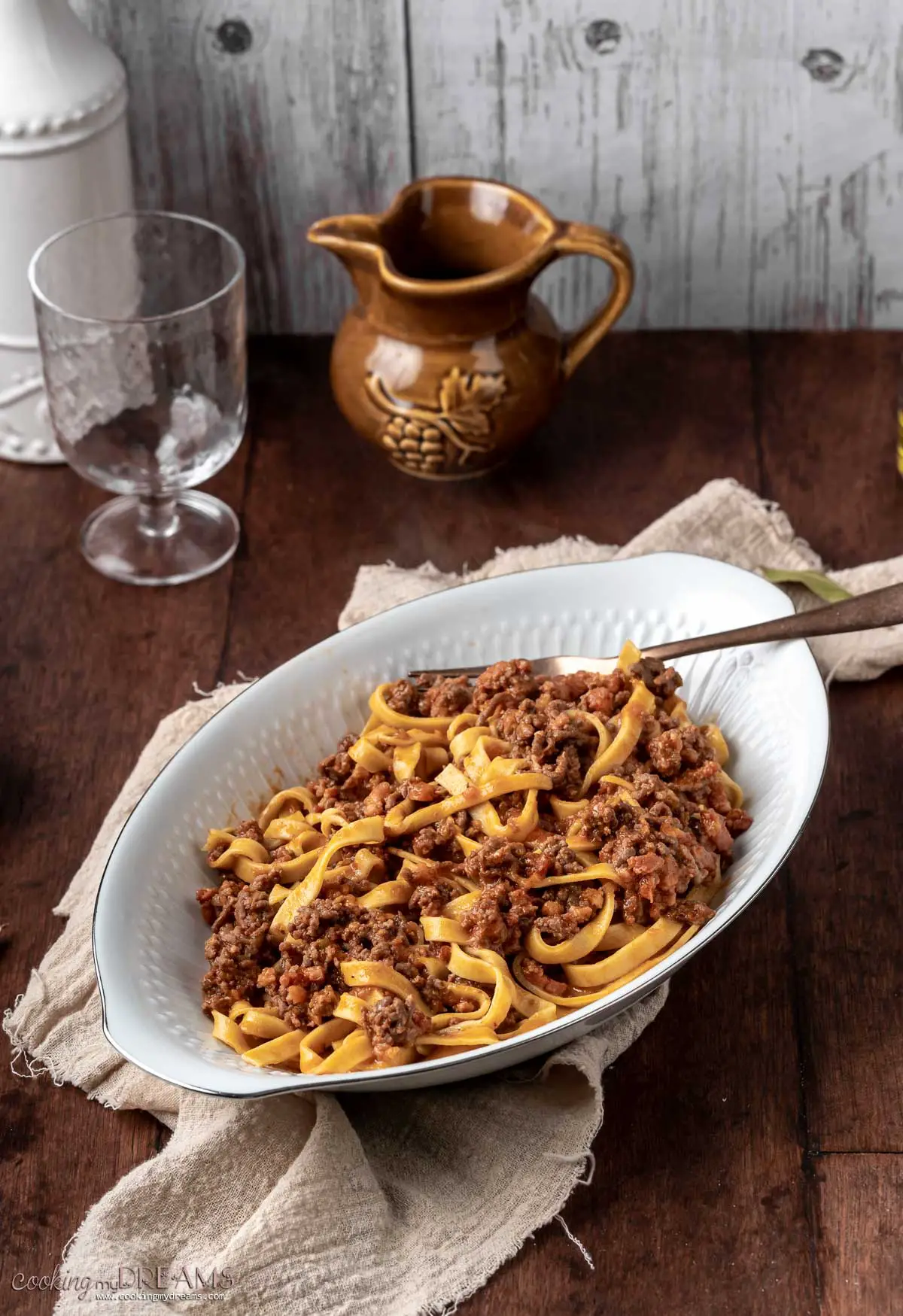 white tray full of tagliatelle bolognese with a serving spoon