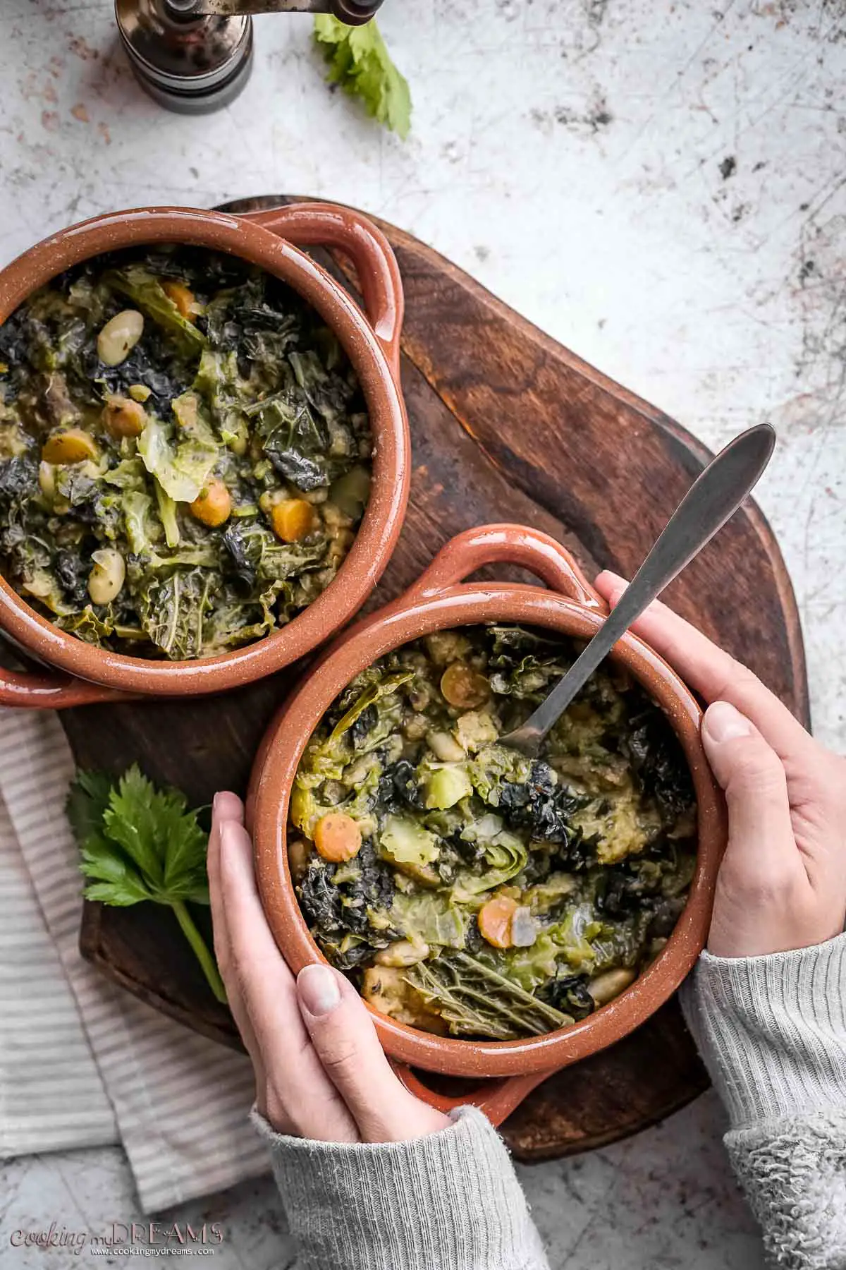 hands holding a terracotta bowl or ribollita stew