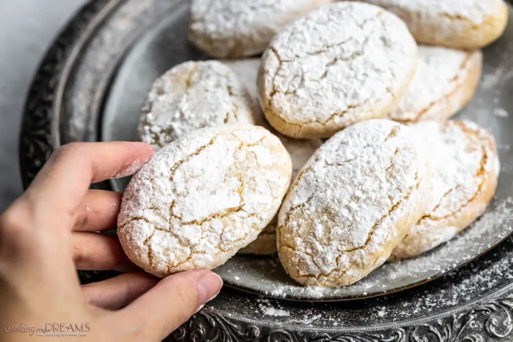 hand taking an italian almond cookie from a plate