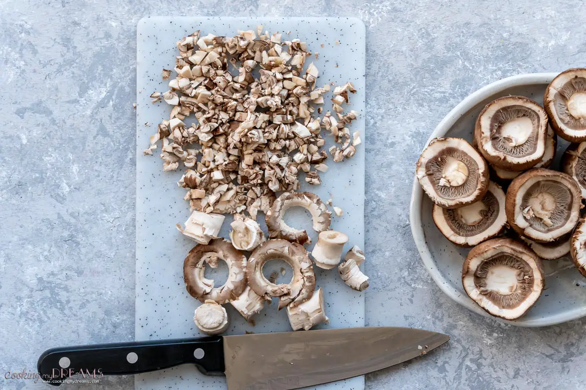 mushrooms cleaned and miced on a cutting board next to a chef knife