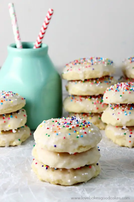 stack of frosted ricotta cookies in front of a green milk bottle