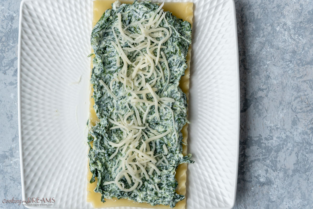spinach and ricotta spread on a lasagna sheet, topped with cheese